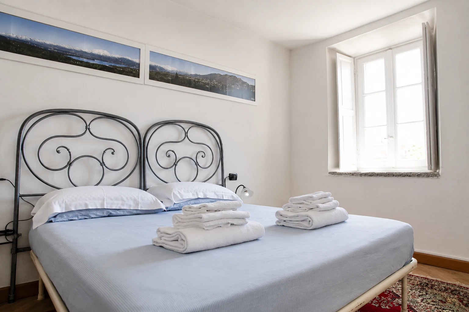 Camera da letto con letto matrimoniale, biancheria chiara e finestra luminosa