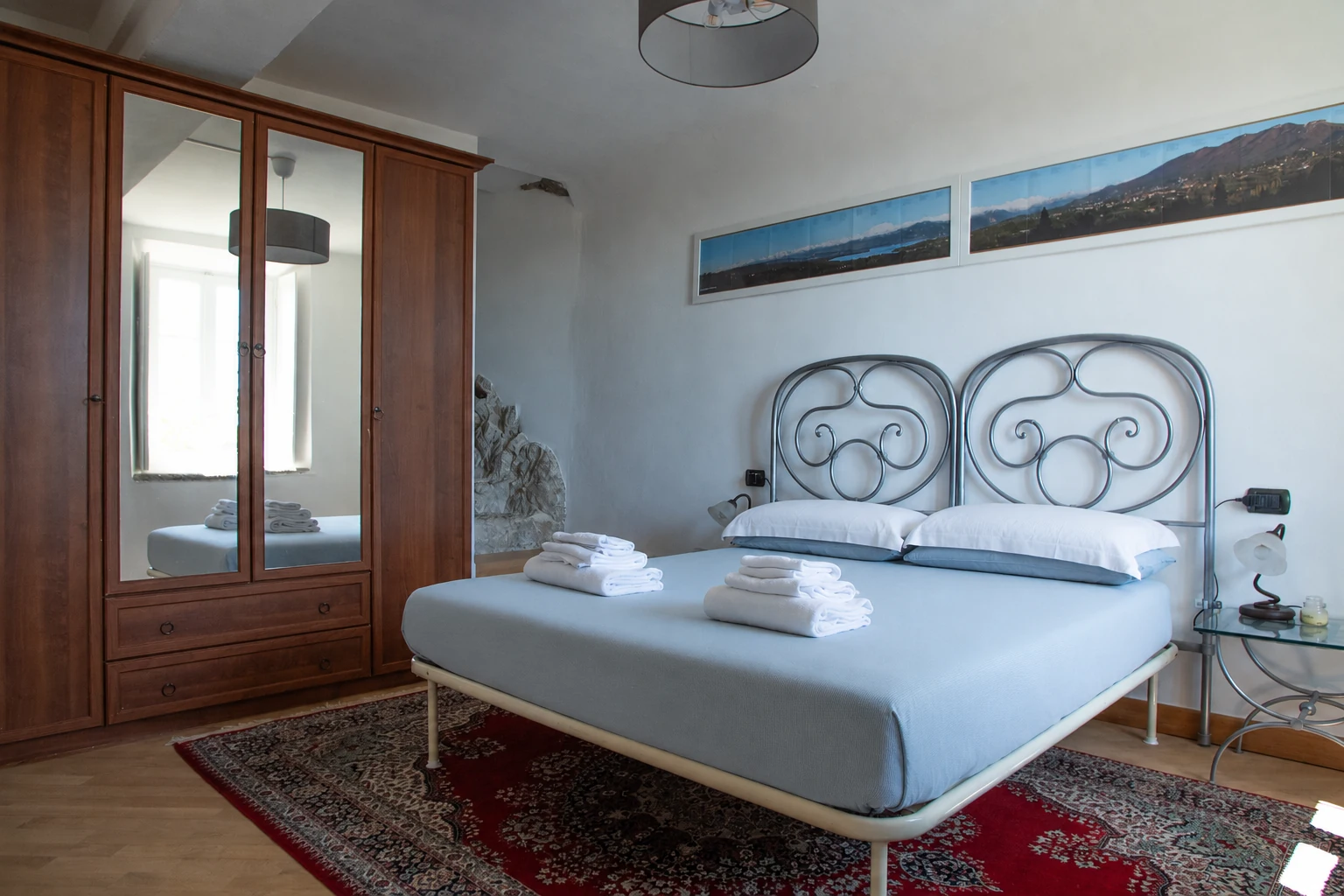 Vista della camera con letto matrimoniale, armadio in legno e tappeto