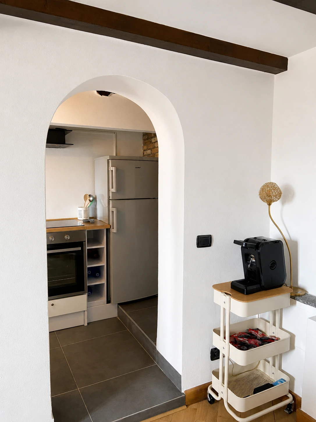 Vista verso la cucina attraverso un arco con macchina del caffè in primo piano
