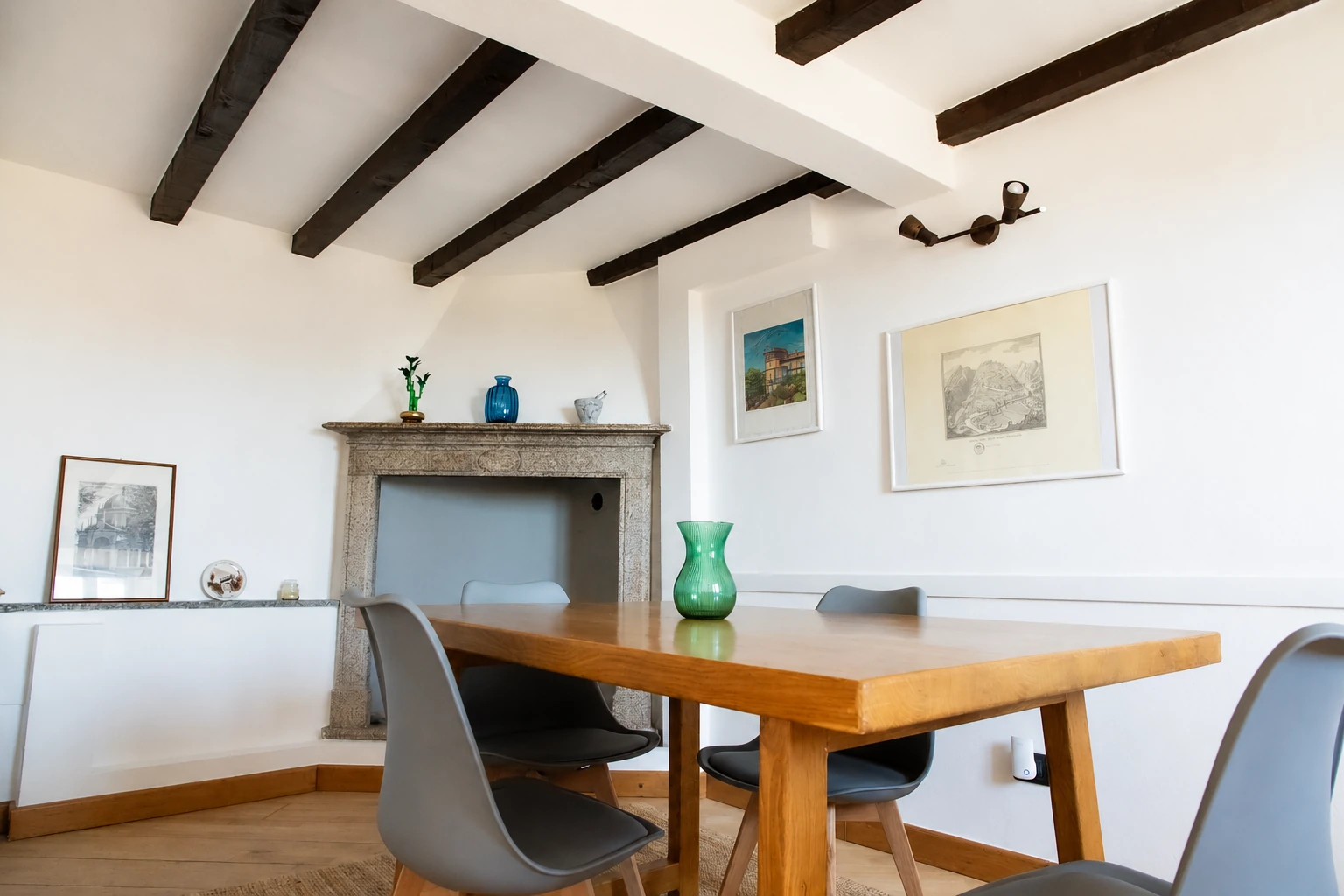 Sala da pranzo della Casa del Convivio con tavolo in legno, travi a vista e camino in pietra